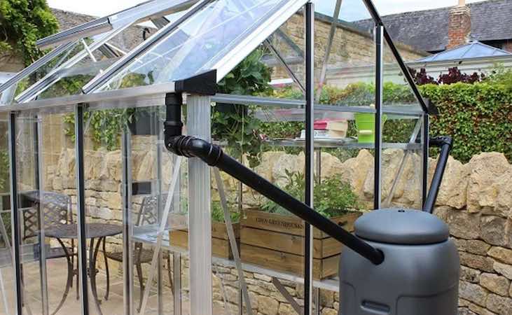 A water butt and downpipe kit connected to the greenhouse guttering